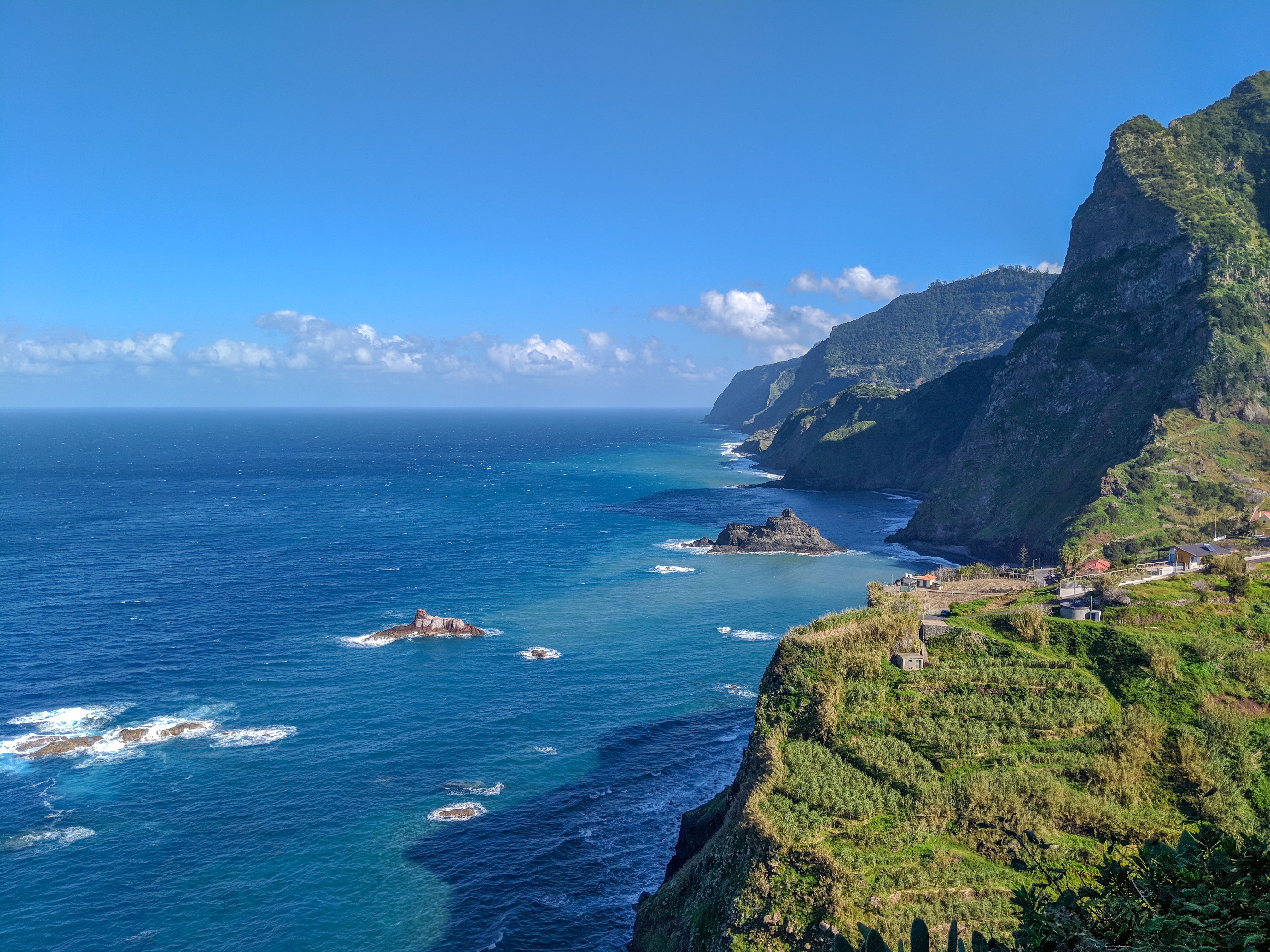 Stunning aerial view of Madeira's cliffs meeting the azure Atlantic Ocean under a bright blue sky. Stunning aerial view of Madeira's cliffs meeting the azure Atlantic Ocean under a bright blue sky.