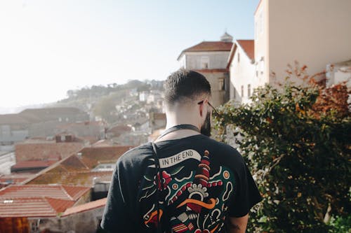 Man Wearing Black T-shirt Standing Near White Concrete Houses