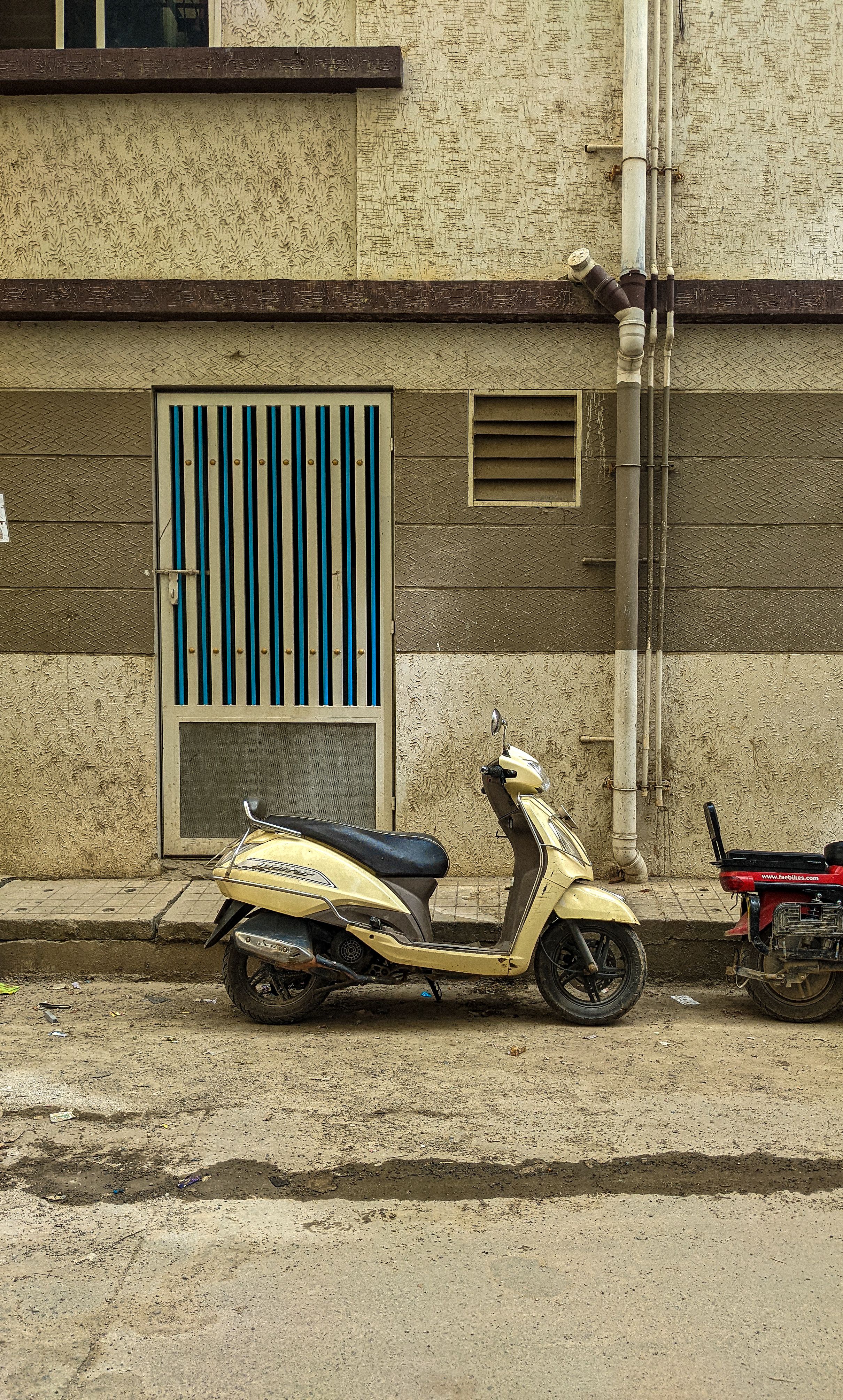 A parked scooter near a doorway on a quiet street in Bengaluru, India.