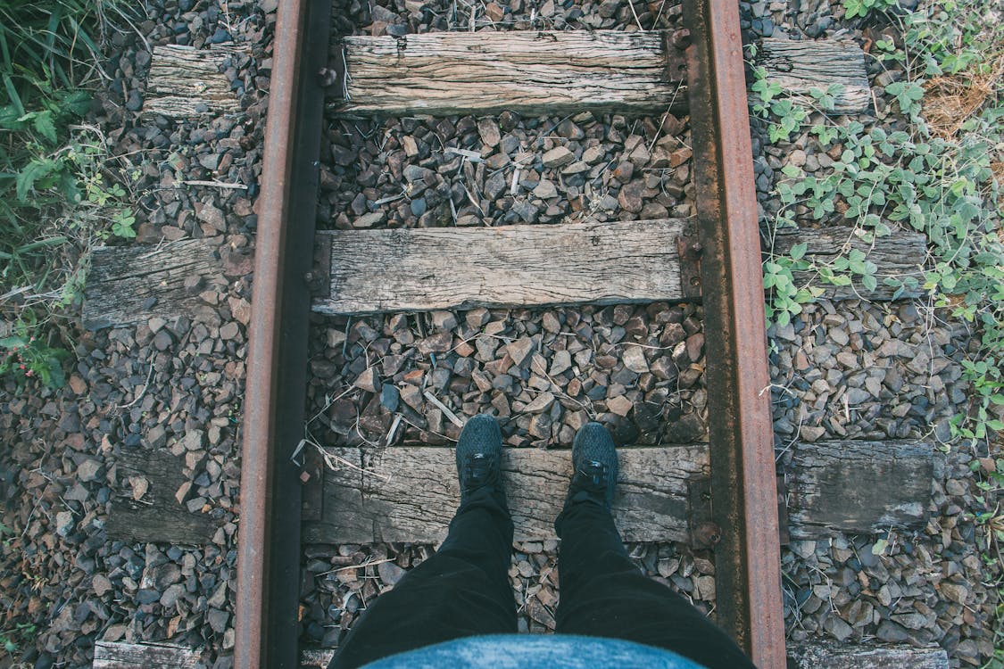 бесплатная Человек в черных облегающих джинсах и кроссовках ступает на деревянную тропу Стоковое фото