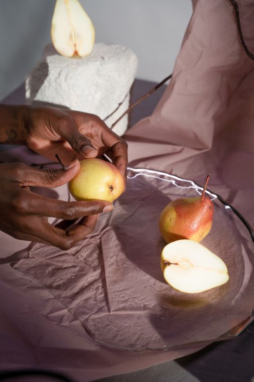 Free Close-up of hands arranging pears for a still life setup on a textured surface. Stock Photo