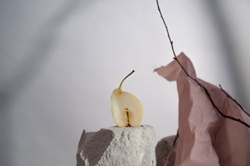 Cut Pear on Stone near Paper and Branch