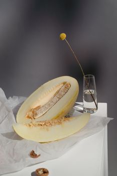 Elegant composition of a sliced melon and delicate flower in glass, showcasing minimalism.
