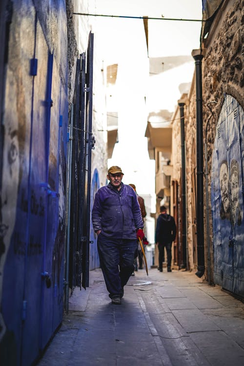 A Man in Blue Jacket Walking on the Street
