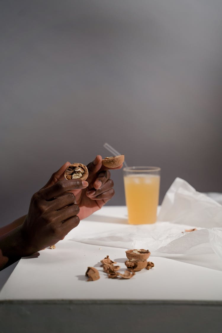 Hands Holding Broken Nuts Near Juice