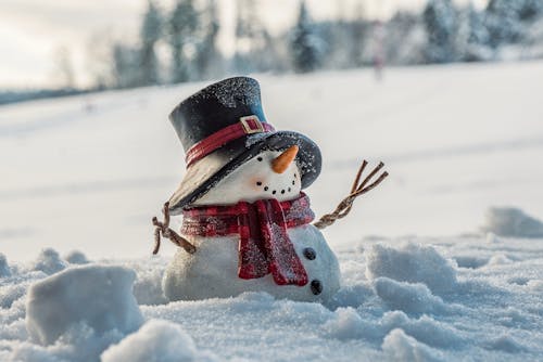 Free Snowman With Black Hat and Red Scarf on a Snow Covered Ground Stock Photo