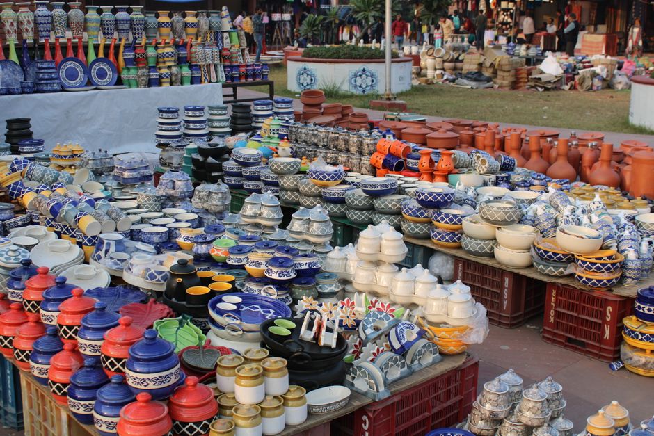 Vibrant ceramic pots and vases on display in an outdoor market setting, showcasing diverse handcrafted designs.