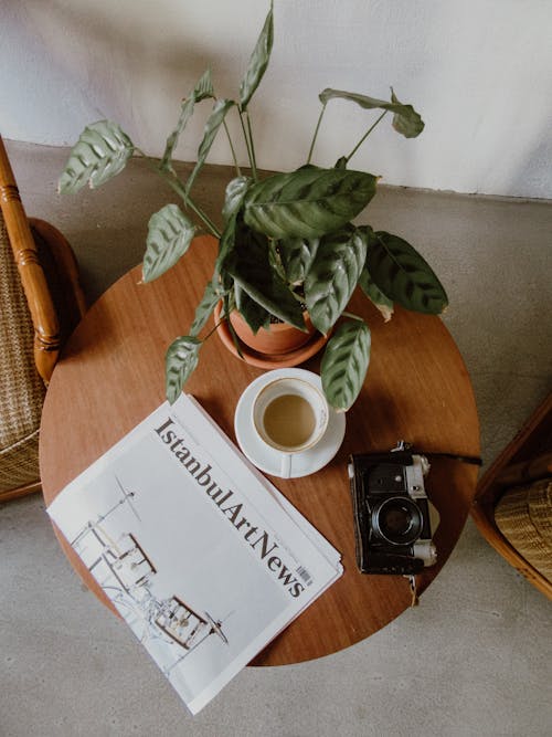 Newspaper Beside a Cup of Coffee and Camera on a Wooden Table