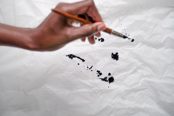 Brush laying black ink strokes on creased paper - photo by Ron Lach on Pexels