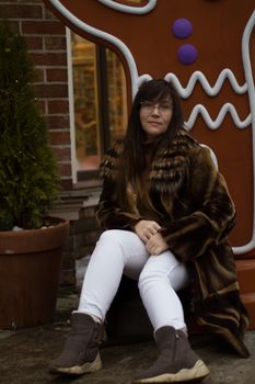 A woman in a fur coat sits amidst holiday decorations, exuding festive warmth.
