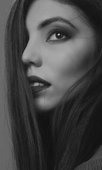 Artistic black and white portrait showcasing a young woman's profile in a studio setting.