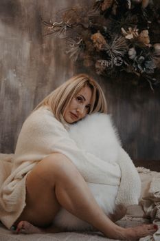 Woman in a knitted sweater sitting indoors, exuding warmth and style in a winter setting.