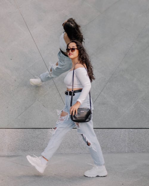 A Woman in White Long Sleeve Shirt Walking on the Street