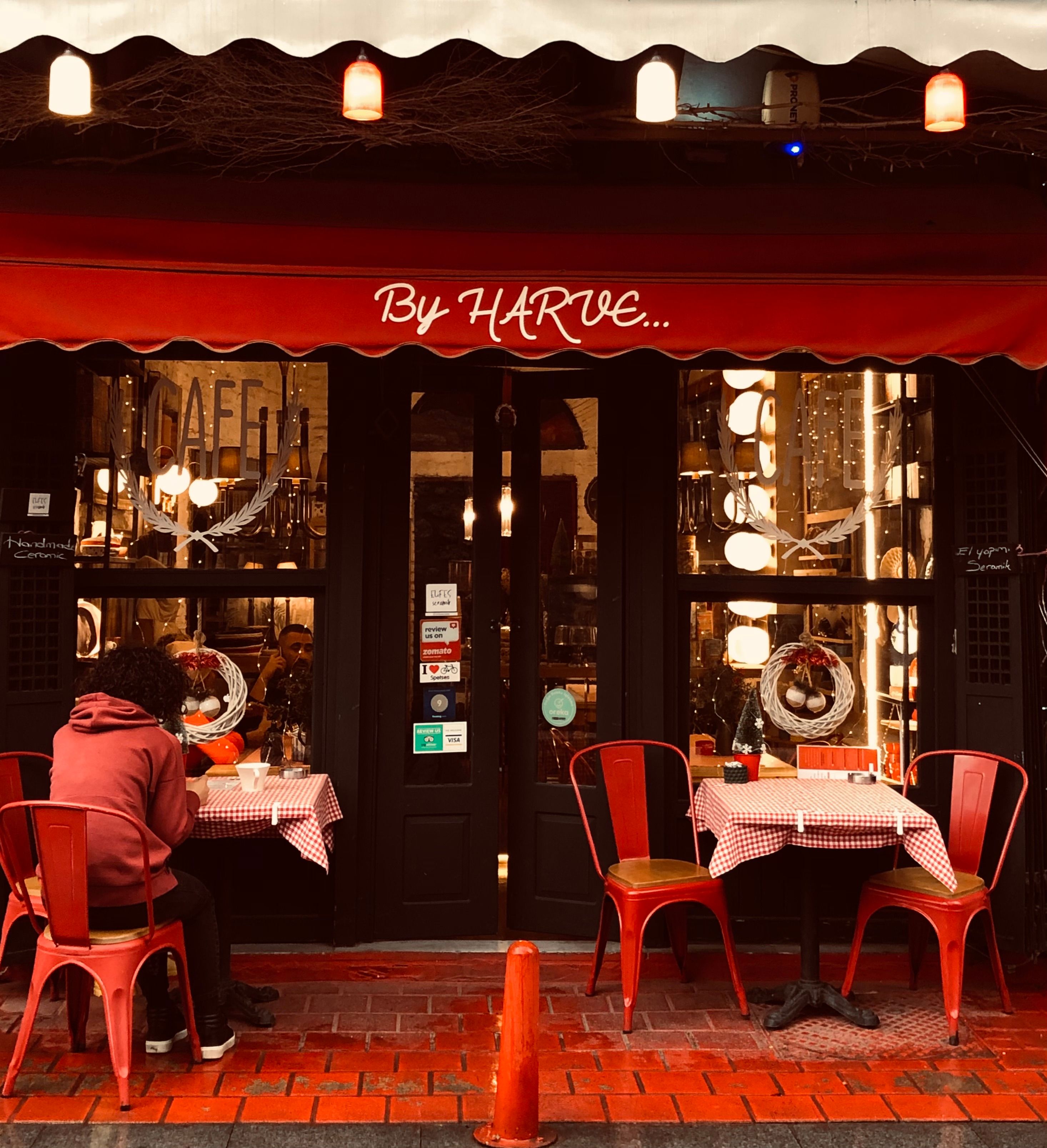 Charming outdoor café setting with warm lighting and red accents, perfect for a night out.