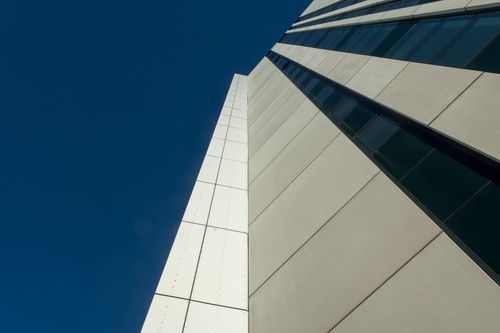 Free Low angle view of a modern skyscraper facade against a clear blue sky. Stock Photo