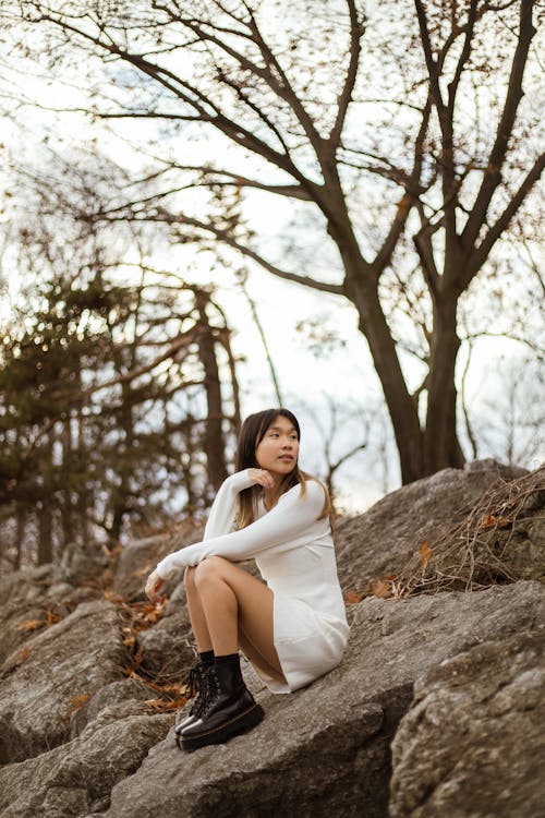 A Woman in White Dress Sitting on a Rock