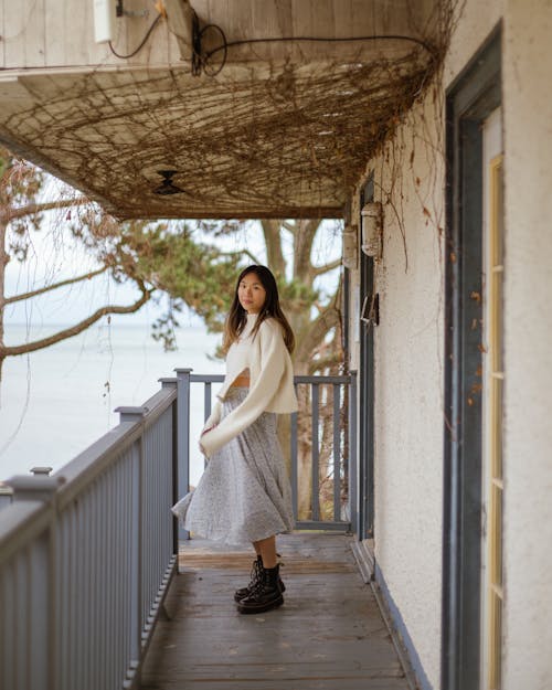 A Woman in White Sweater Standing on the Balcony