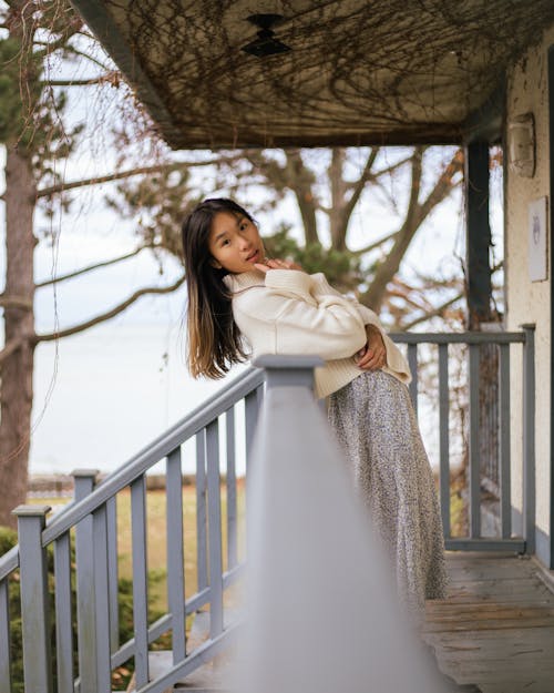 Girl in White Knitted Sweater Leaning on Wooden Railing