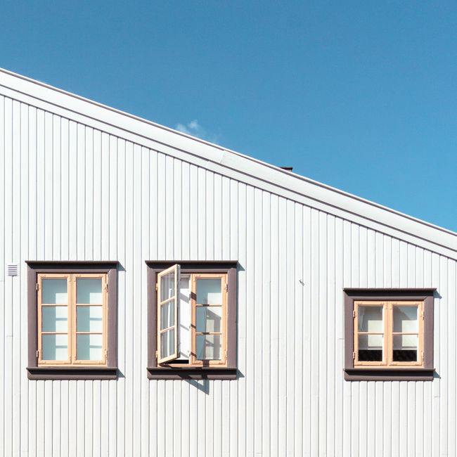 White building facade with open windows against a blue sky in Fredrikstad, Norway.