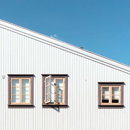 Free White building facade with open windows against a blue sky in Fredrikstad, Norway. Stock Photo
