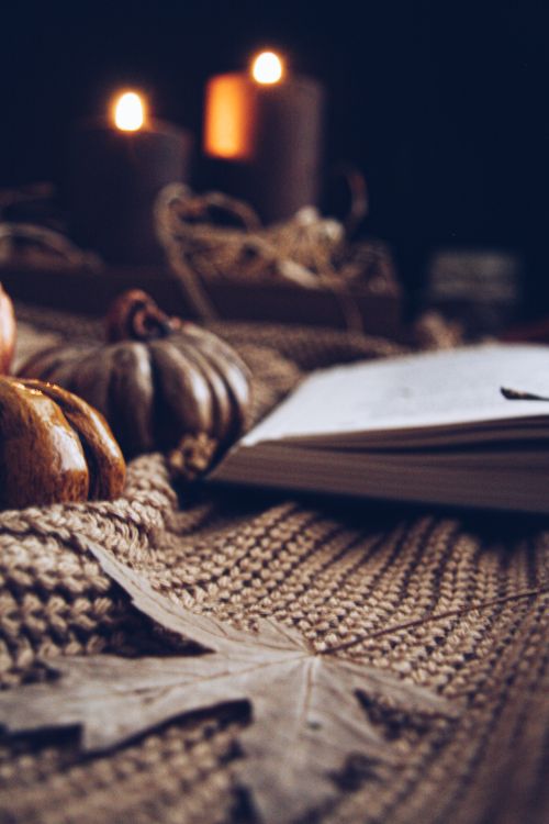 Free Warm autumn scene featuring candles, pumpkins, and a knitted fabric for a cozy atmosphere. Stock Photo