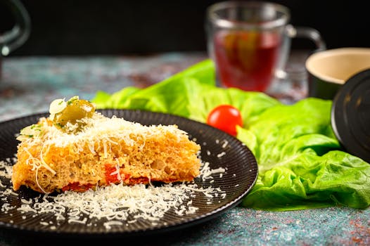 A slice of gourmet bread topped with cheese and olive, surrounded by fresh lettuce and tomato.