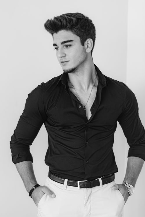 Free Black and white portrait of a stylish young man in a dress shirt posing against a plain background. Stock Photo