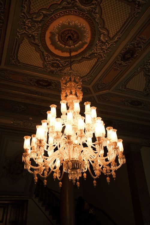 Free Stunning crystal chandelier illuminating a richly decorated ornate ceiling. Stock Photo