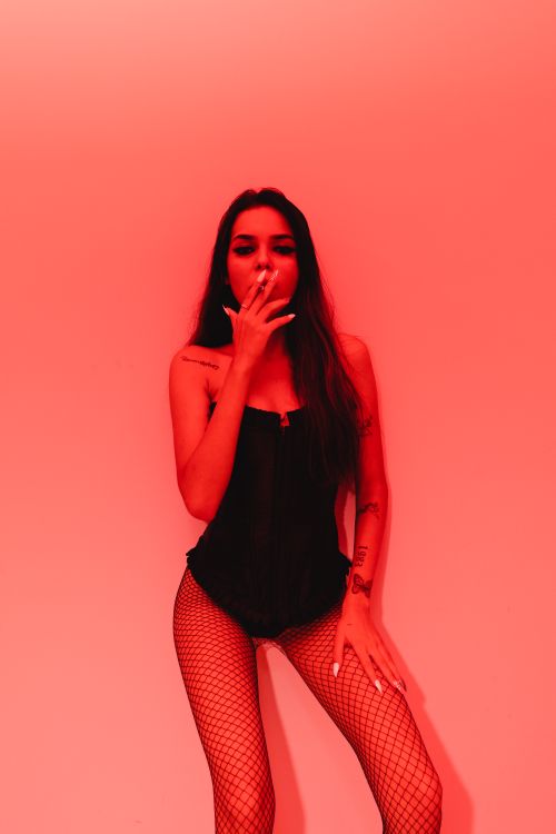 Free A woman in lingerie poses against a red backdrop, exuding sensuality and confidence. Stock Photo