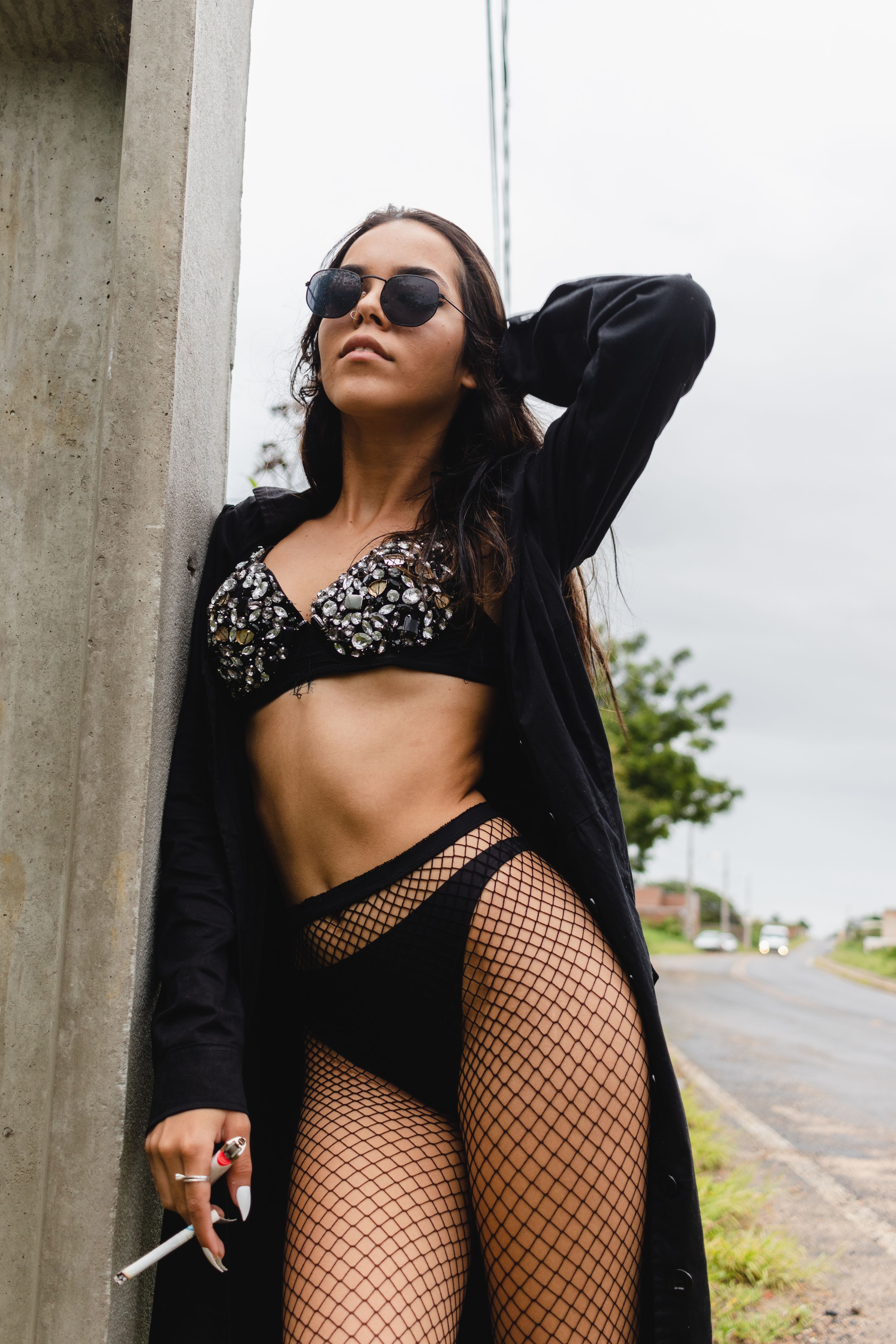 Mulher confiante posando em lingerie estilosa ao ar livre em um dia nublado.