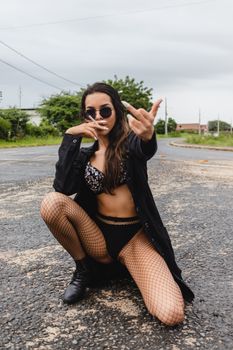 Confident woman in sunglasses and fishnets posing outdoors. Street style fashion.