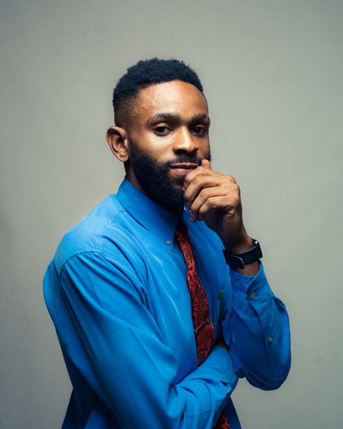 Free Black man with facial hair in blue shirt poses confidently in a studio setting. Stock Photo
