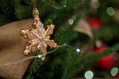 Free Close-up of a golden snowflake ornament hanging on a decorated Christmas tree. Stock Photo