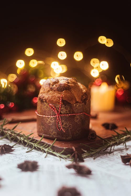 A Close Up on a Muffin on Table Decorated in Christmas Style With Christmas Decorations and Lights in Background 