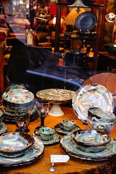 Vibrant handmade dinnerware elegantly displayed in a cozy shop window with warm lighting.