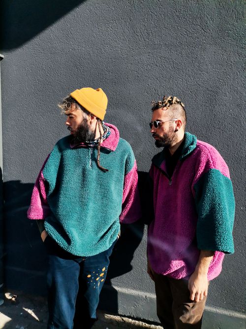 Free Two men wearing colorful fleece jackets and beanies pose stylishly outdoors. Stock Photo