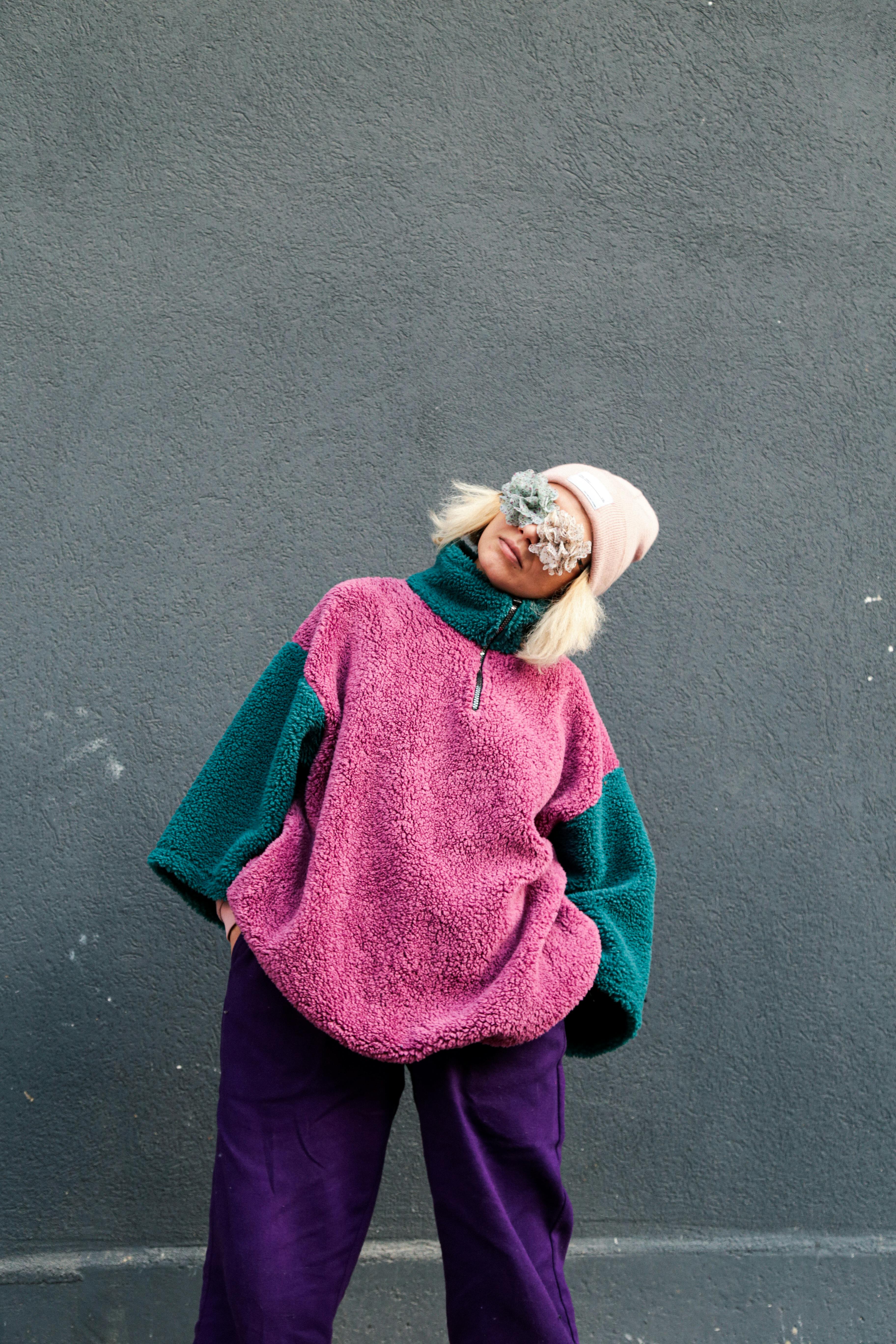 Woman in colorful winter clothing against a gray wall, exuding modern style and warmth.