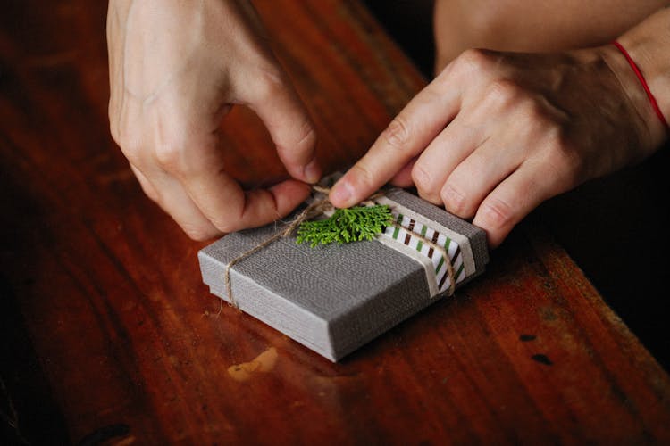 A Hand Opening The Gray Box On A Wooden Surface