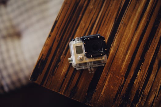 A close-up shot of a compact action camera on a rustic wooden table, highlighting its portability.