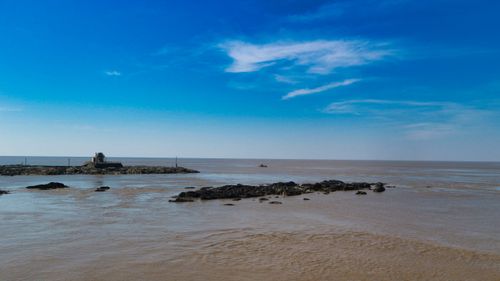Free Calm ocean view with rocks and blue sky, perfect for a serene escape. Stock Photo
