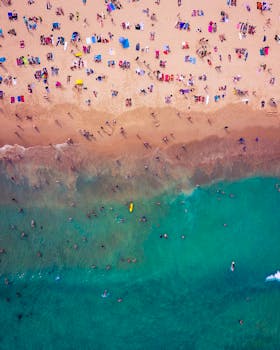 A vibrant aerial shot of Bondi Beach, Australia, crowded with sunbathers and swimmers on a sunny day.