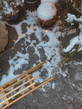 Overhead view of a snowy outdoor scene with a wooden sled and string lights.