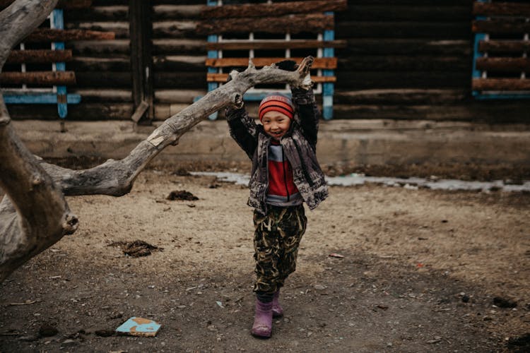 A Kid Hanging On The Thick Branch Of A Tree