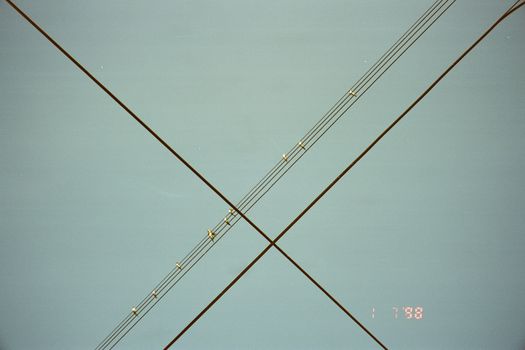 Minimalistic view of intersecting power lines set against a clear blue sky, symbolizing connectivity.