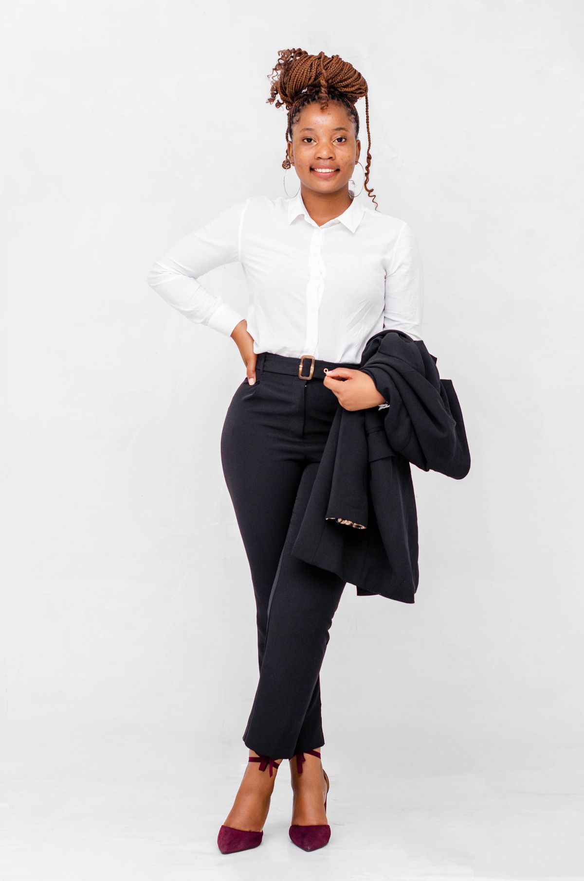 Professional model wearing a white shirt and black tailored trousers, holding a blazer