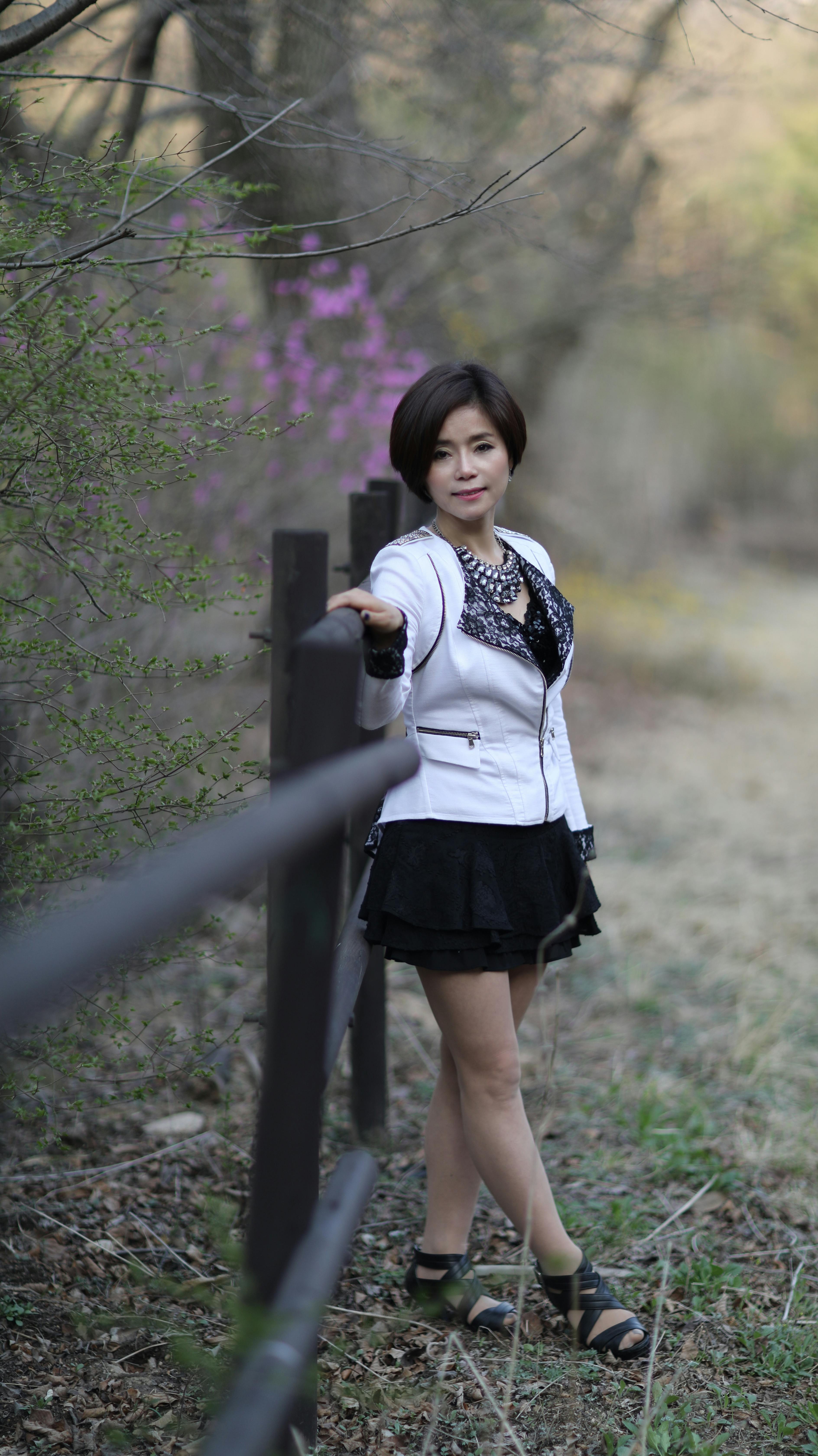 Stylish woman in a nature setting, exuding elegance and confidence in a fashionable outfit.