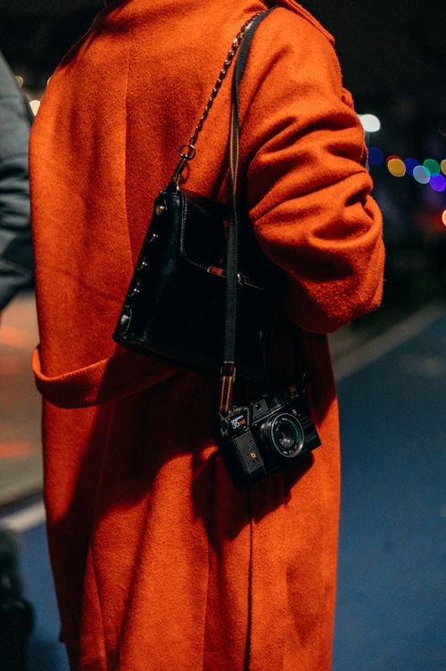Free Stylish individual wearing an orange coat and carrying a vintage camera, embodying urban fashion in Istanbul. Stock Photo