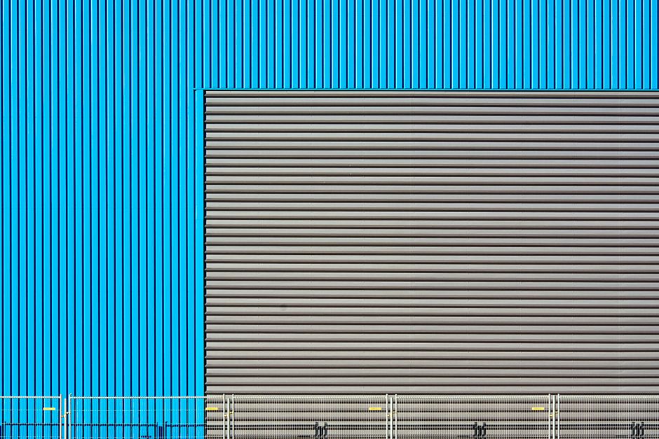 Close-up of an industrial building facade with blue and grey corrugated metal patterns.