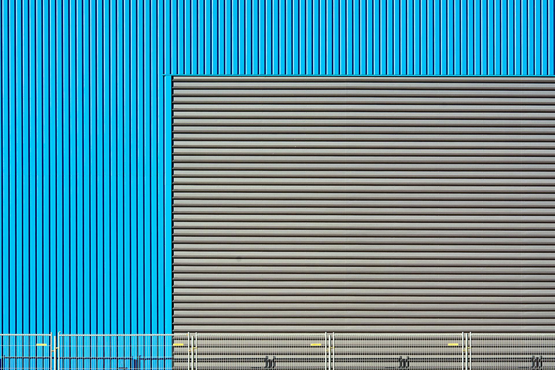 Close-up of an industrial building facade with blue and grey corrugated metal patterns.