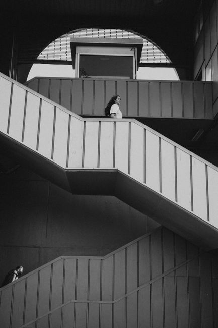 Monochrome image of people on a modern indoor staircase with geometric design.
